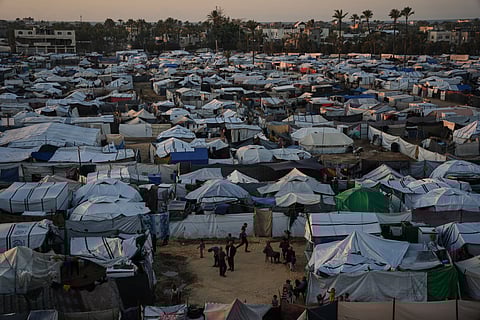 Displaced Palestinians gather outside a tent at a temporary camp in Deir al-Balah, central Gaza Strip, Wednesday, Nov. 26, 2025.