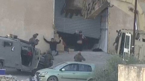 This image taken from video by Palestine TV shows two Palestinian men kneeling on the ground to Israeli forces shortly before they were shot dead during a military operation in Jenin, West Bank, on Thursday, Nov. 27, 2025.