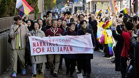 Plaintiffs of same-sex couples march towards a high court, walking along people gathering before its ruling on same-sex marriage in Tokyo, Friday, Nov. 28, 2025.