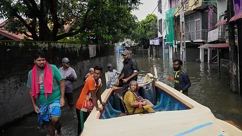 Volunteers help carry an old woman to a boat as they shift her to a safe place from a submerged neighborhood in Colombo, Sri Lanka, Saturday, Nov, 29, 2025.