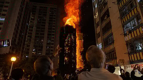 People look at flames engulfing a building after a fire broke out at Wang Fuk Court, a residential estate in the Tai Po district of Hong Kong's New Territories, Wednesday, Nov. 26, 2025.