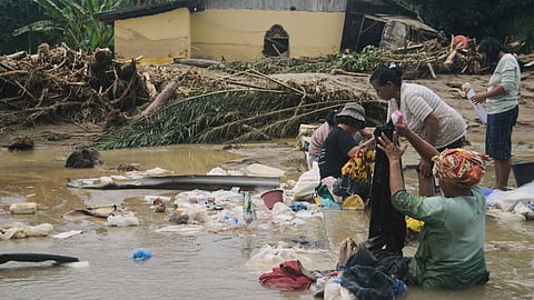 People use flood water to remove mud from clothing at a village hit by a flash flood in Batang Toru, North Sumatra, Indonesia, Saturday, Nov. 29, 2025.
