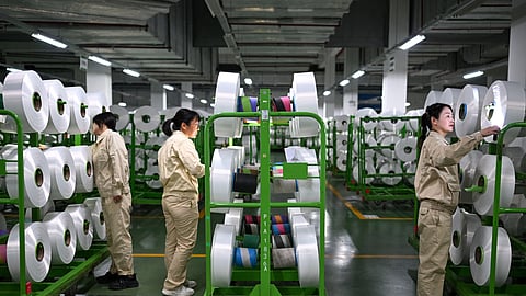Workers check on the products in the world's largest production base for recycled polyester filament yarn, in Siyang, in east China's Jiangsu province, on Oct. 24, 2025.