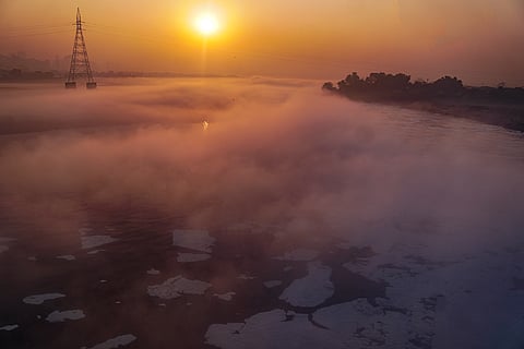Morning sun rises over a fog-covered stretch of the Yamuna river with toxic foam floating on its waters, at Kalindi Kunj in New Delhi, Monday, Dec. 1, 2025.