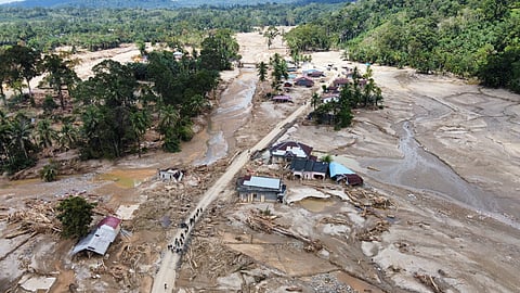 People walk along a road in a village affected by a flash flood in Batang Toru, North Sumatra, Indonesia, Monday, Dec. 1, 2025.