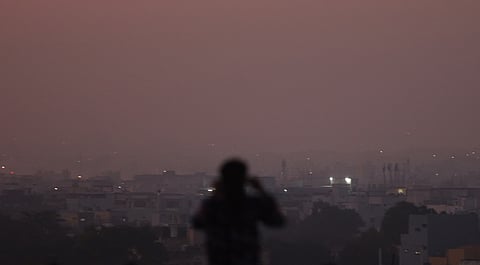 A hazy silhouette of a man standing against the smoggy city skyline in the backdrop.