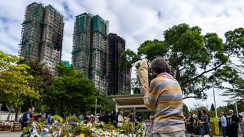 People offer flowers for the victims near the site of a deadly fire at Wang Fuk Court, a residential estate in the Tai Po district of Hong Kong's New Territories, on Tuesday, Dec 2, 2025.
