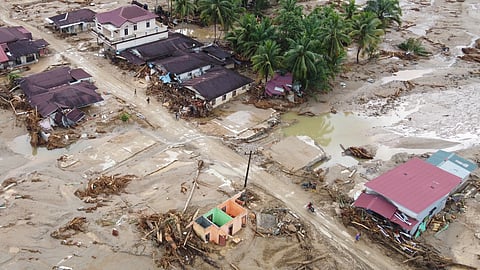 In this aerial photo taken using a drone, people are seen making their way on a muddy road at a village affected by a flash flood in Batang Toru, North Sumatra, Indonesia, Tuesday, Dec. 2, 2025.