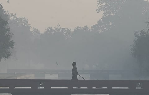 Pedestrian walk at a park near India Gate amid smoggy conditions in New Delhi on Monday.