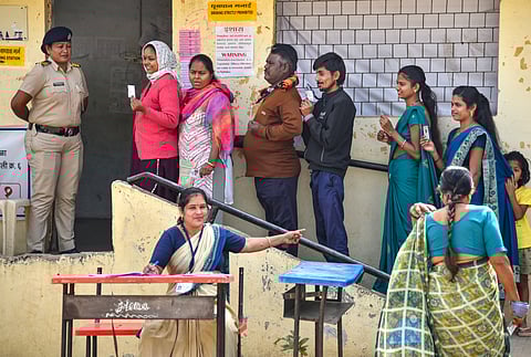 People wait in a queue to cast their votes at a polling booth during the Maharashtra local body, in Nagpur, Tuesday, Dec. 2, 2025.