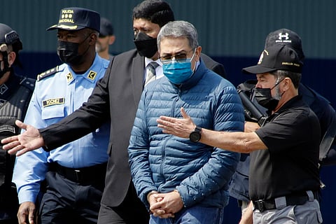 Former Honduran President Juan Orlando Hernandez, second from right, is taken in handcuffs to a waiting aircraft as he is extradited to the United States, at an Air Force base in Tegucigalpa, Honduras, April 21, 2022.