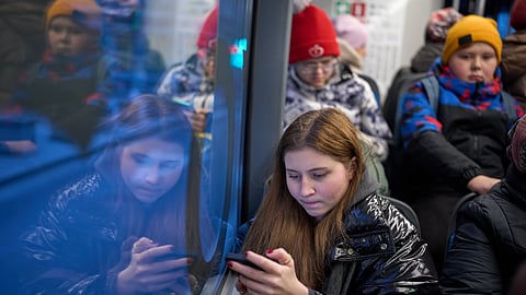 FILE - A woman looks at her smartphone on a bus in Moscow, Russia, Wednesday, Dec. 3, 2025