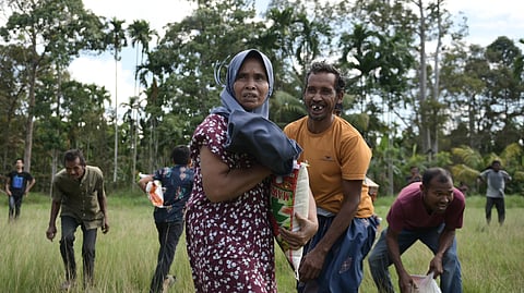 Flood survivors react as they receive relief goods during an aerial aid distribution using the national disaster mitigation agency's helicopter in North Aceh, Indonesia, Thursday, Dec. 4, 2025.