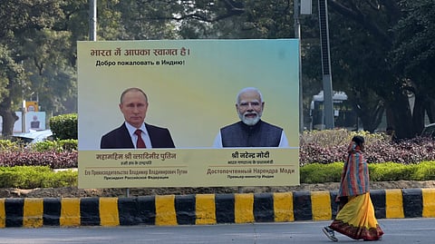 Commuters move past a hoarding with portraits of Russia President Vladimir Putin and Prime Minister Narendra Modi in New Delhi on Thursday.