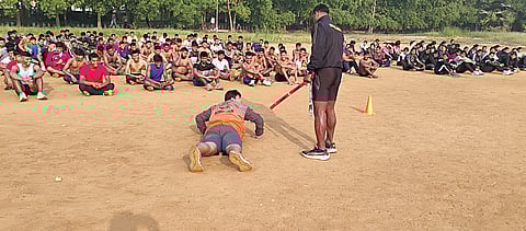 A gathering of around 700 strictly disciplined young men and women pushing their limits, resembling the rigorous drill of an army battalion under the stern eyes of two supervisors.
