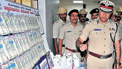 City Police Commissioner Seemanth Kumar Singh takes a look at the seized cash around 19 lakhs by Jnanabharathi police from two frauds posed as Ayurvedic medicine distributors, in Bengaluru on Wednesday.