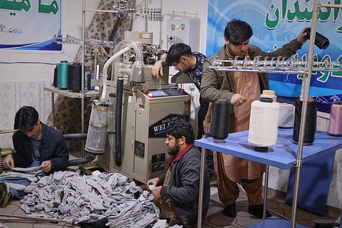 Local businessman Mohammad Amiri, 35, right, sorts out spools of thread for making socks as he works with his staff, all people with disabilities, in his sock production workshop in the western Afghan city of Herat, Afghanistan, Monday, Dec. 8, 2025