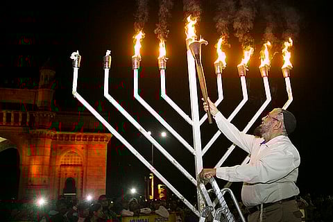 A man from the Indian Jewish community lighting the nine flames of Menorah near the Gateway of India, Mumbai