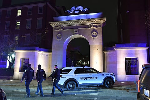 Law enforcement officials walk near an entrance to Brown University in Providence, R.I., on Saturday, Dec. 13, 2025, during the investigation of a shooting.