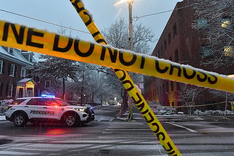 A police vehicle is parked at an intersection near crime scene tape at Brown University, Sunday, Dec. 14, 2025.