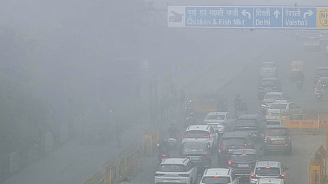 Vehicles move along a road amid fog on a cold winter morning, in New Delhi, Monday, Dec. 15, 2025.