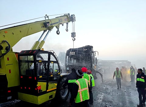 Cranes clear the charred remains of buses after a fog-hit pile-up involving several buses and cars triggered fires on the Yamuna Expressway, in Mathura, Tuesday, Dec. 16, 2025