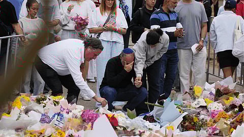 People react during a menorah lighting ceremony at a floral memorial for victims of Sunday's shooting, at the Bondi Pavilion on Bondi Beach.