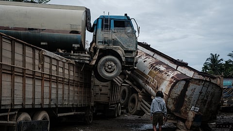 Palm oil tankers lie in a damaged state following a flash flood at a vehicle repair workshop in Aceh Tamiang, Northern Sumatra, on December 15, 2025.