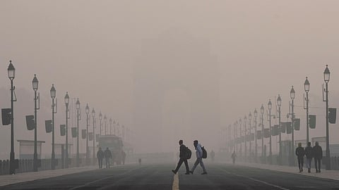 Visitors walk across the Kartavya Path near the India Gate on a smoggy winter morning, in New Delhi, Wednesday, Dec. 17, 2025.