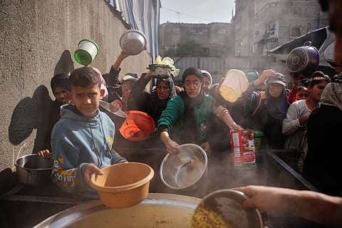 Palestinian women struggle to receive donated food at a community kitchen in Nuseirat, central Gaza Strip, Wednesday, Dec. 17, 2025.