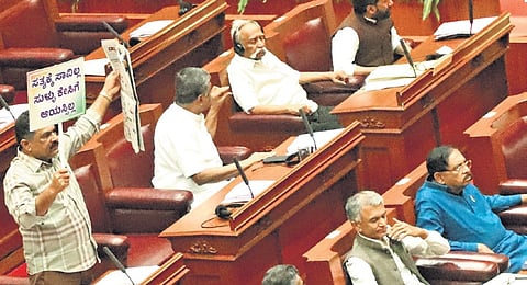 A Congress MLC holds placards in the Council in Belagavi on Wednesday