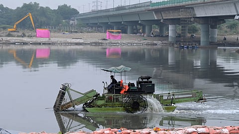 Workers clean Vasudev Ghat Yamuna river a day after Chhath puja in New Delhi on Tuesday.