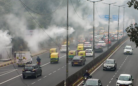 Water sprinklers operate under dense fog on a winter morning, in New Delhi, Saturday, Dec. 20, 2025.