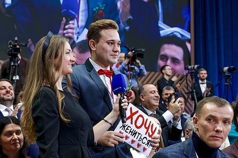 Kirill Bazhanov of Yekaterinburg’s Channel 4, center, asks a question, holding a sign he wanted to get married, during Russian President Vladimir Putin's annual news conference at Gostinny Dvor in Moscow, on Friday, Dec 19, 2025.