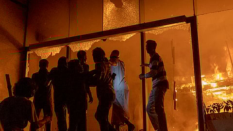 People are seen at the entrance to the Daily Star building as it burns in Dhaka on December 19, 2025, amid protests following the news of the death of youth leader Sharif Osman Hadi.