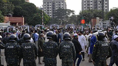 Security forces stand guard at the entrance of the nation's Parliament complex as people arrive to perform funeral prayers for leading Bangladeshi activist Sharif Osman Hadi, who died from gunshot wounds sustained in an attack in Dhaka earlier this month, in Dhaka, Bangladesh, Saturday, Dec. 20, 2025.