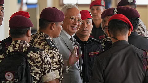 Former Malaysian Prime Minister Najib Razak, center, is escorted by prison officers on his arrival at the Kuala Lumpur High Court Complex, in Kuala Lumpur, Malaysia, Monday, Dec. 22, 2025.