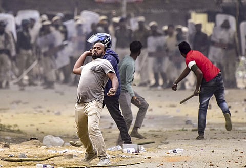 People throw stones during a clash between two groups over the issue of eviction, at Kheroni in West Karbi Anglong district, Assam.