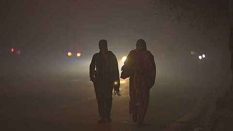 People take a walk on a road amid dense fog on a winter morning in New Delhi on Tuesday.