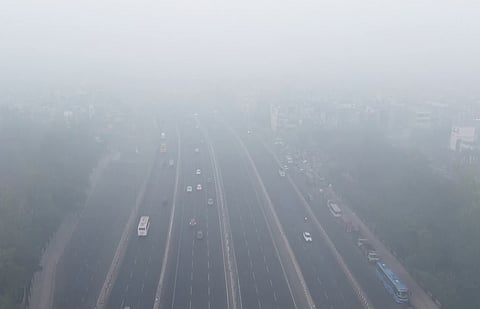 Commuters move through a thick layer of smog in the Vinod Nagar area amid severe air quality across the national capital region.