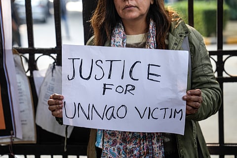 A protester holds a placard during a demonstration against the suspension of the jail term of Kuldeep Sengar, a former BJP MLA who was convicted in the Unnao rape case, outside the Delhi High Court, in New Delhi, Friday, Dec. 26, 2025.
