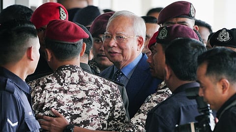 Malaysian former Prime Minister Najib Razak, center, is escorted by prison officers on his arrival at the Kuala Lumpur High Court complex in Kuala Lumpur, Malaysia, Oct. 30, 2024.