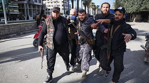 A police officer injured by a thrown stone is helped away from the area after clashes erupted between Alawite protesters from the Alawite religious minority and counterprotesters, two days after a bomb in an Alawite mosque in Homs killed eight people and wounded 18 during Friday prayers, in Latakia, Syria's coastal region, Sunday, Dec. 28, 2025.
