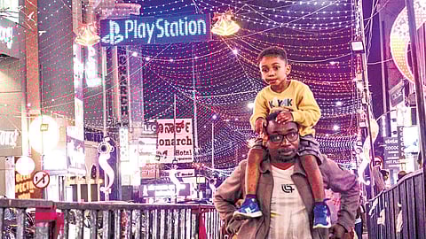 A foreigner with his son on his shoulders takes a walk at Brigade road underneath the light installations for New Year celebrations