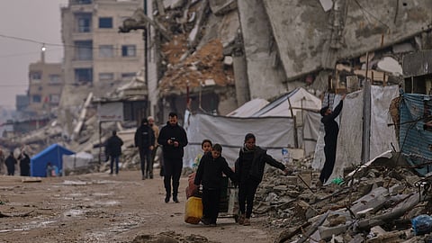 Palestinians walk along a street surrounded by buildings destroyed during Israeli air and ground operations in the Sheikh Radwan neighbourhood, in Gaza City, Tuesday, Dec. 30, 2025.