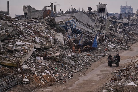A Palestinian woman walks along a street surrounded by buildings destroyed during Israeli air and ground operations in the Sheikh Radwan neighborhood, in Gaza City, Tuesday, Dec. 30, 2025.