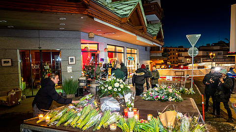 A woman lays flowers at the site where a fire ripped through a crowded bar in the Alpine ski resort town of Crans-Montana on January 1, 2026.