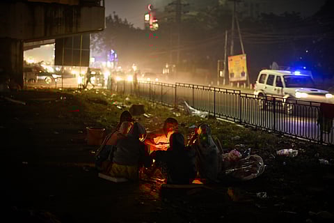A destitute family living under Khandagiri flyover sit around a bonfire to get rid of cold in Bhubaneswar on Sunday evening.