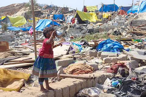 A girl drinks water standing amidst the rubble caused by the eviction drive at Kogilu, Bengaluru.
