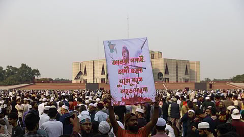 A Bangladeshi mourner holds a poster bearing the portrait of deceased youth leader Sharif Osman Hadi during his funeral in Dhaka on December 20, 2025.